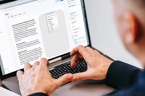 Person sitting at a computer with notebook and training displaying on the computer